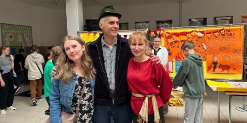 Nauczyciel w kapeluszy bawarskim i obok dwie nauczycielki pozują do zdjęcia