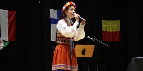 Uczennica w stroju ludowym śpiewa na scenie